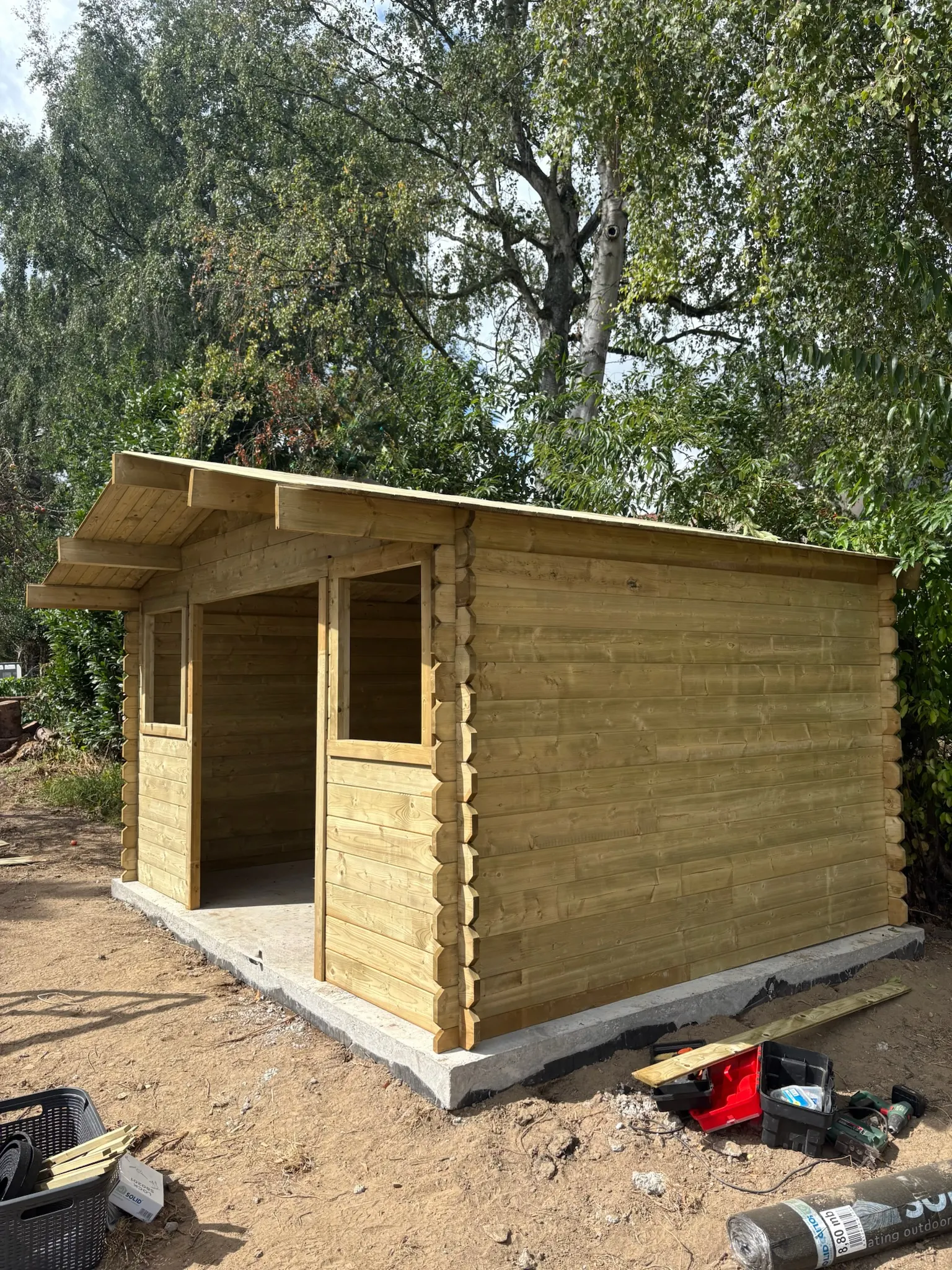 Abri de jardin neuf en bois clair posé sur une dalle béton