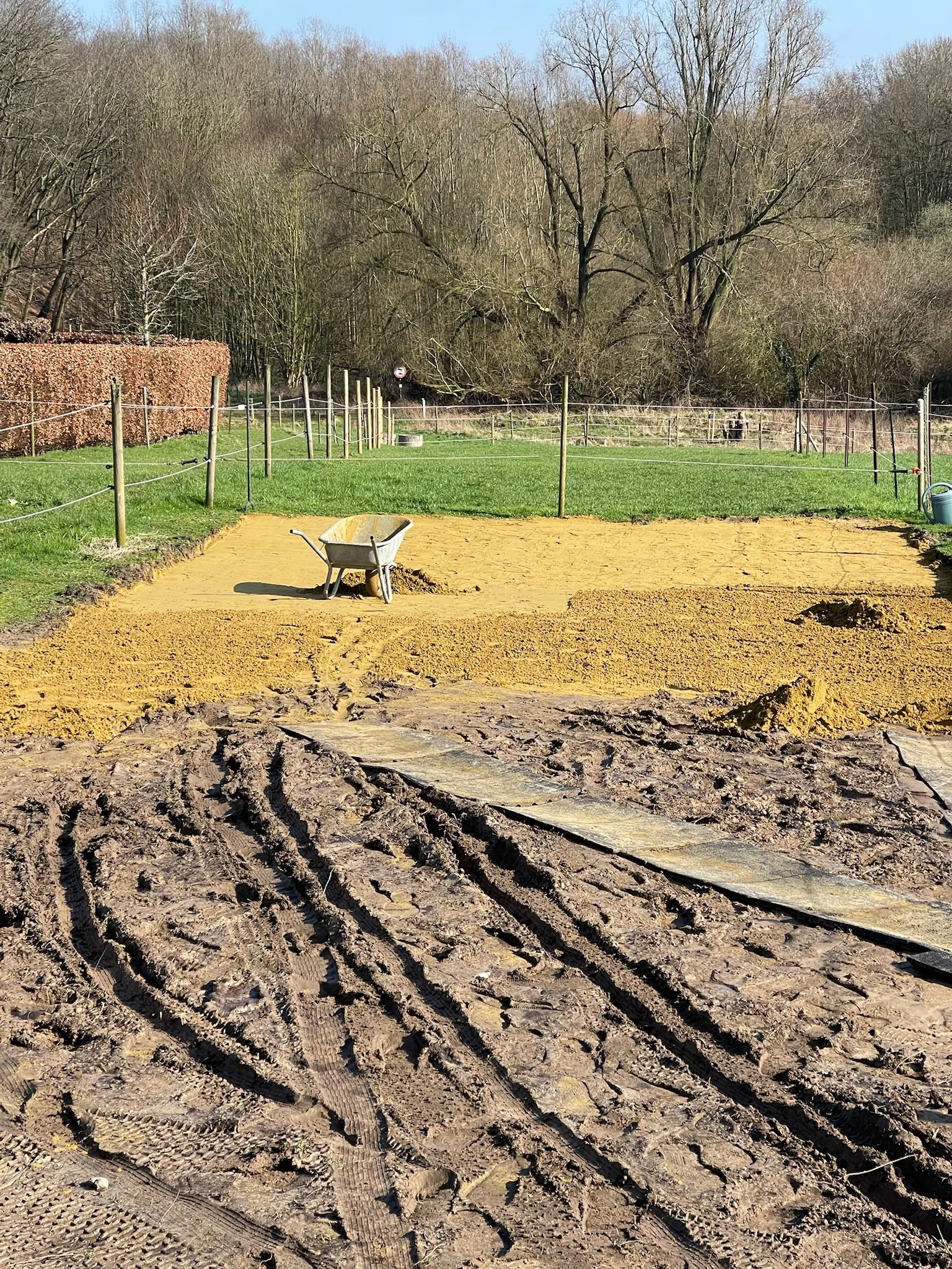 Zone de sable jaune réglée avec une brouette, au bord d’une prairie