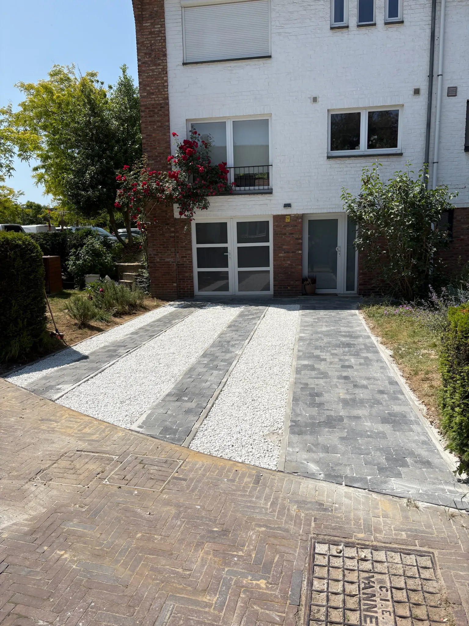 Allée de garage alternant bandes de pavés anthracite et de gravier blanc
