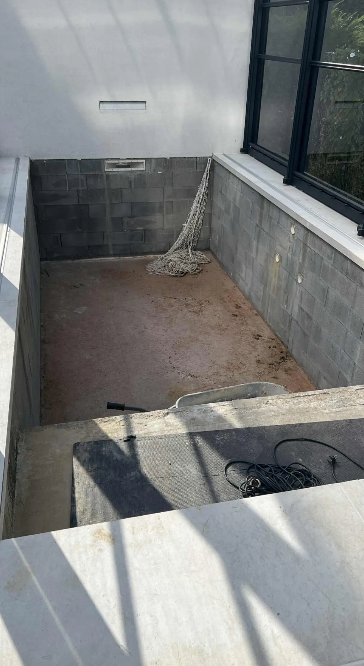 Avant : bassin en blocs de béton brut sous un abri vitré