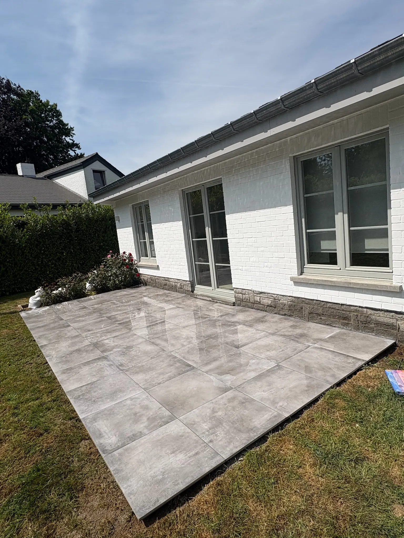 Terrasse en grandes dalles grises devant une maison blanche