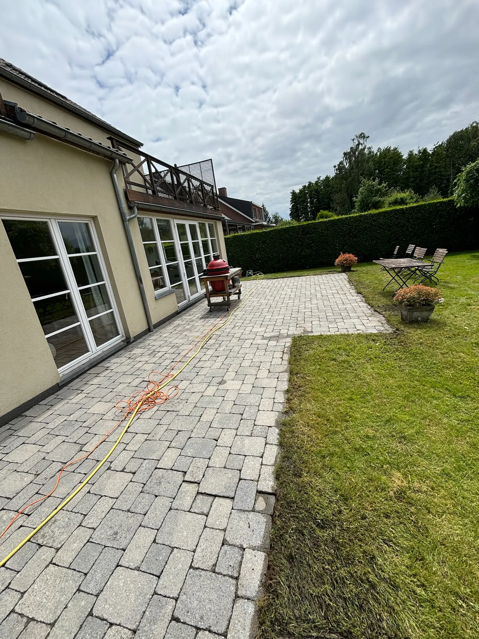 Longue terrasse en pavés gris-beige d’aspect ancien le long d’une façade